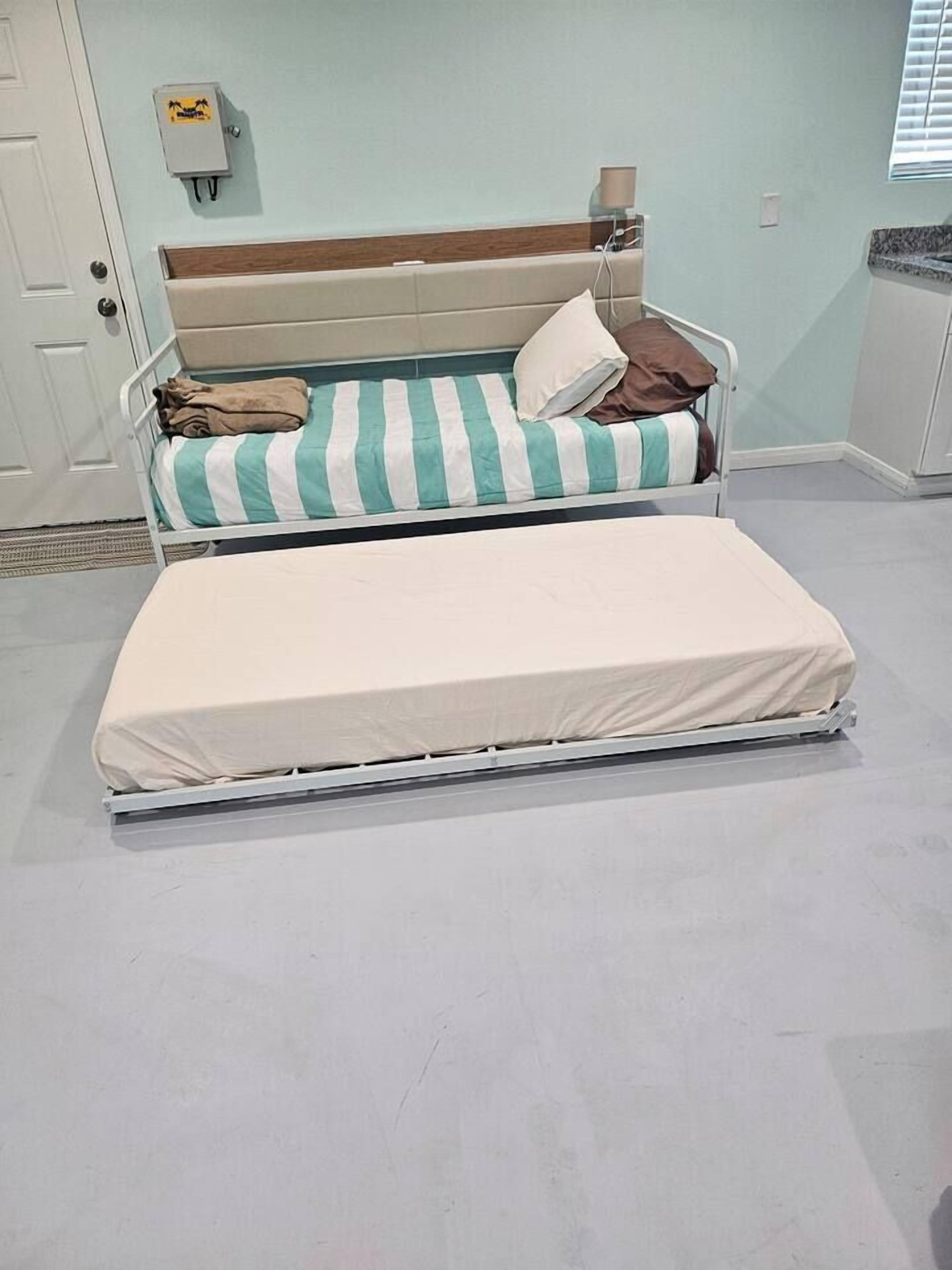 A double bed with a striped pillow and a plain mattress.