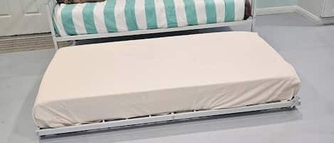 A double bed with a striped pillow and a plain mattress.