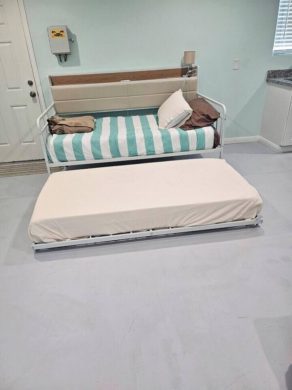 A double bed with a striped pillow and a plain mattress.
