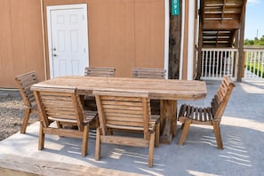 A wooden outdoor table and chairs set on a concrete patio.