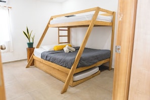 Una cama litera con estructura de madera, una planta en maceta y una mesita de noche.