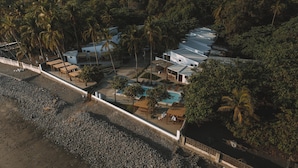 Vue aérienne d’un complexe hôtelier comprenant plusieurs bâtiments, une piscine et une plage.