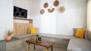 Un salon moderne avec un canapé, une petite table en bois et des œuvres d’art décoratives au mur.