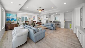 A spacious living room with a sectional sofa, a coffee table, and a ceiling fan. - Sandcastle by Ryson Vacation Rentals (Galveston)