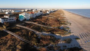 A coastal area with a beach, houses, and a wooden boardwalk. - Sandcastle by Ryson Vacation Rentals (Galveston)