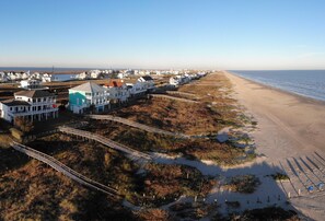 A coastal area with a beach, houses, and a wooden boardwalk. - Sandcastle by Ryson Vacation Rentals (Galveston)