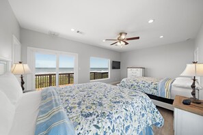 A bedroom with two beds, a ceiling fan, and a balcony with a view. - Sandcastle by Ryson Vacation Rentals (Galveston)