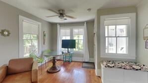 Un salon avec un canapé en cuir marron, une table basse ronde en verre, une table d’appoint turquoise et un banc blanc agrémenté d’un coussin à motifs.