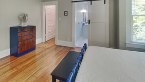 Une chambre à coucher avec un lit, une commode, un ventilateur, une porte et une fenêtre.