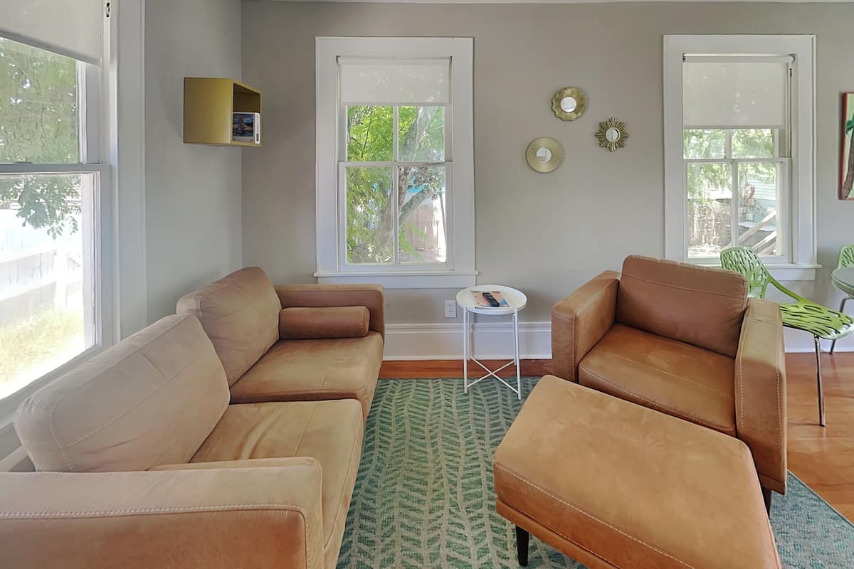 A living room with two leather sofas, a small white side table, and a patterned rug.
