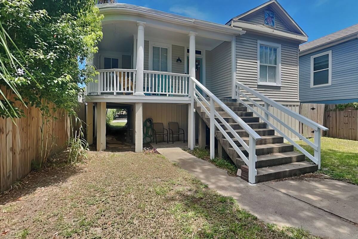 Une maison à deux étages dotée d’un porche et d’un escalier menant à l’étage supérieur.