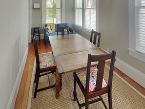 A dining room with a wooden table and chairs, a blue sofa, and a small stool.