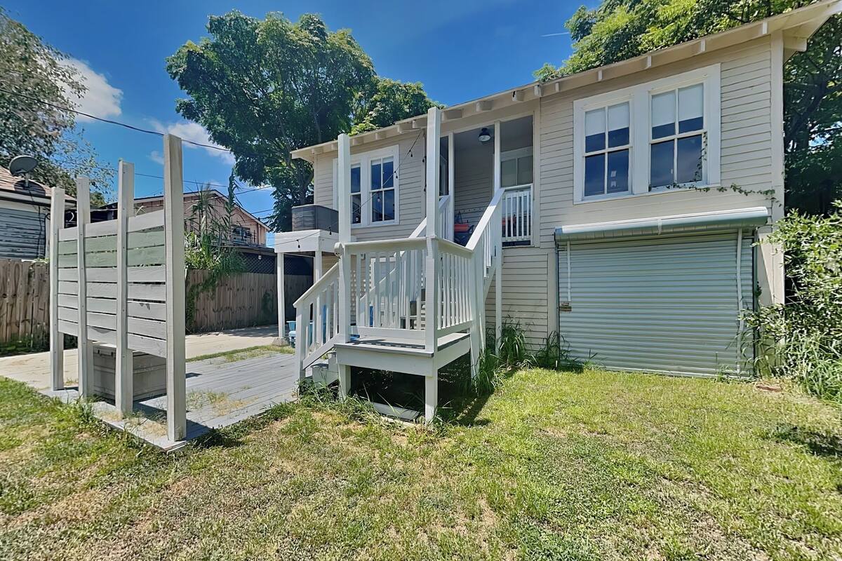 Une maison à deux étages avec une terrasse à l’avant, un garage et une cour arrière clôturée.