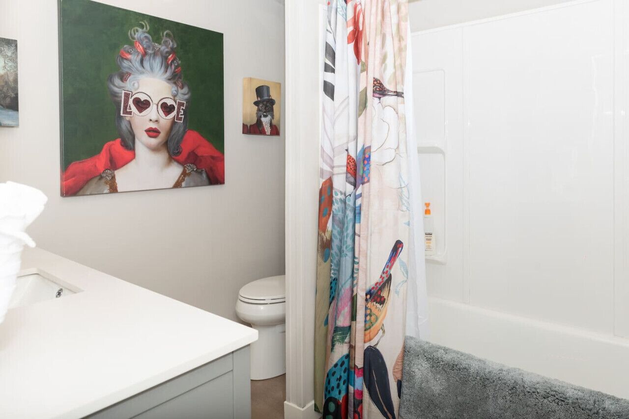 A bathroom with a white sink, toilet, and shower curtain with a colorful design.