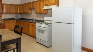 A kitchen with wooden cabinets, a gas stove, a white refrigerator, and a dining table with chairs.