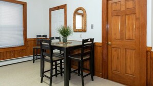 A dining area with a wooden table and chairs, a potted plant, and a mirror on the wall.