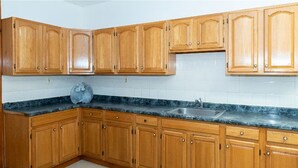 A kitchen with wooden cabinets, a granite countertop, and a stainless steel sink.