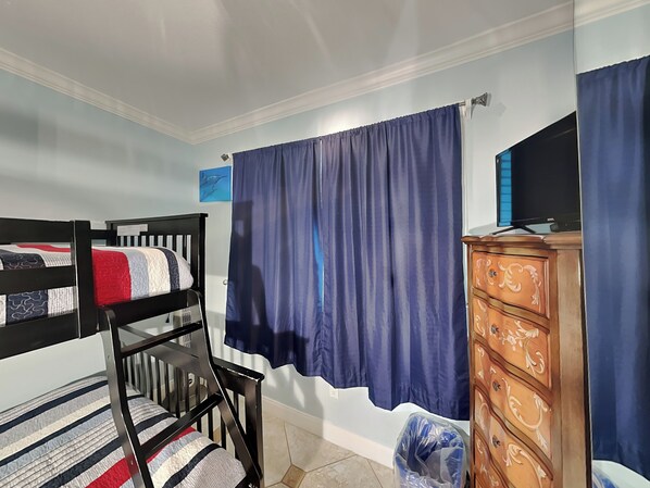 A bedroom with bunk beds, a dresser, a television, and a curtain. - Seascape 2112-Dolphin Lair by Ryson Vacation Rentals (Galveston)