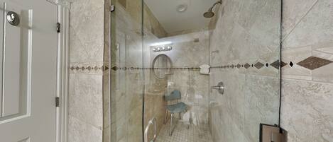 A modern bathroom with a glass-enclosed shower, a vanity with a mirror, and a tiled floor.
