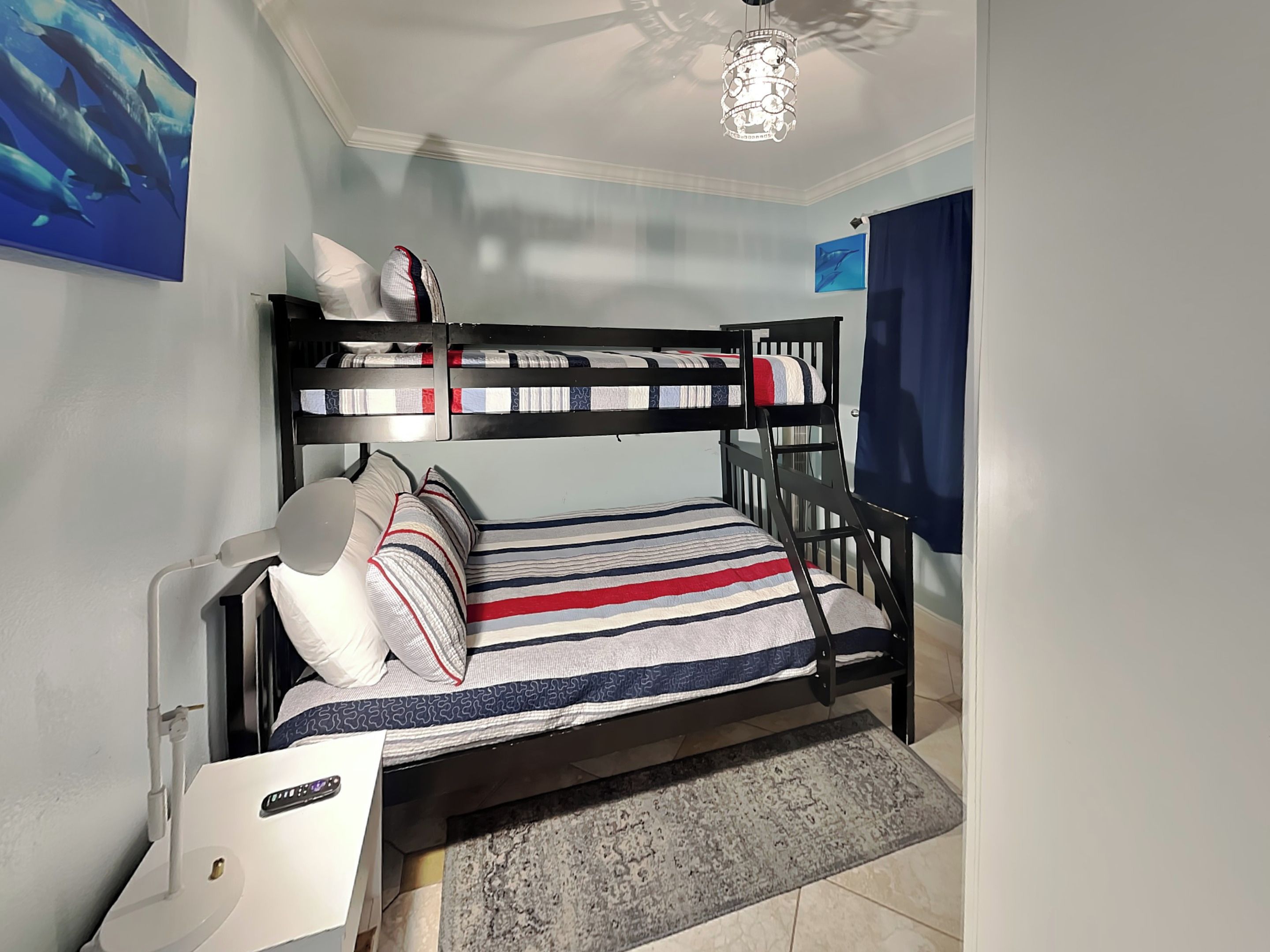 A bunk bed room with striped bedding, a desk, and a radiator.