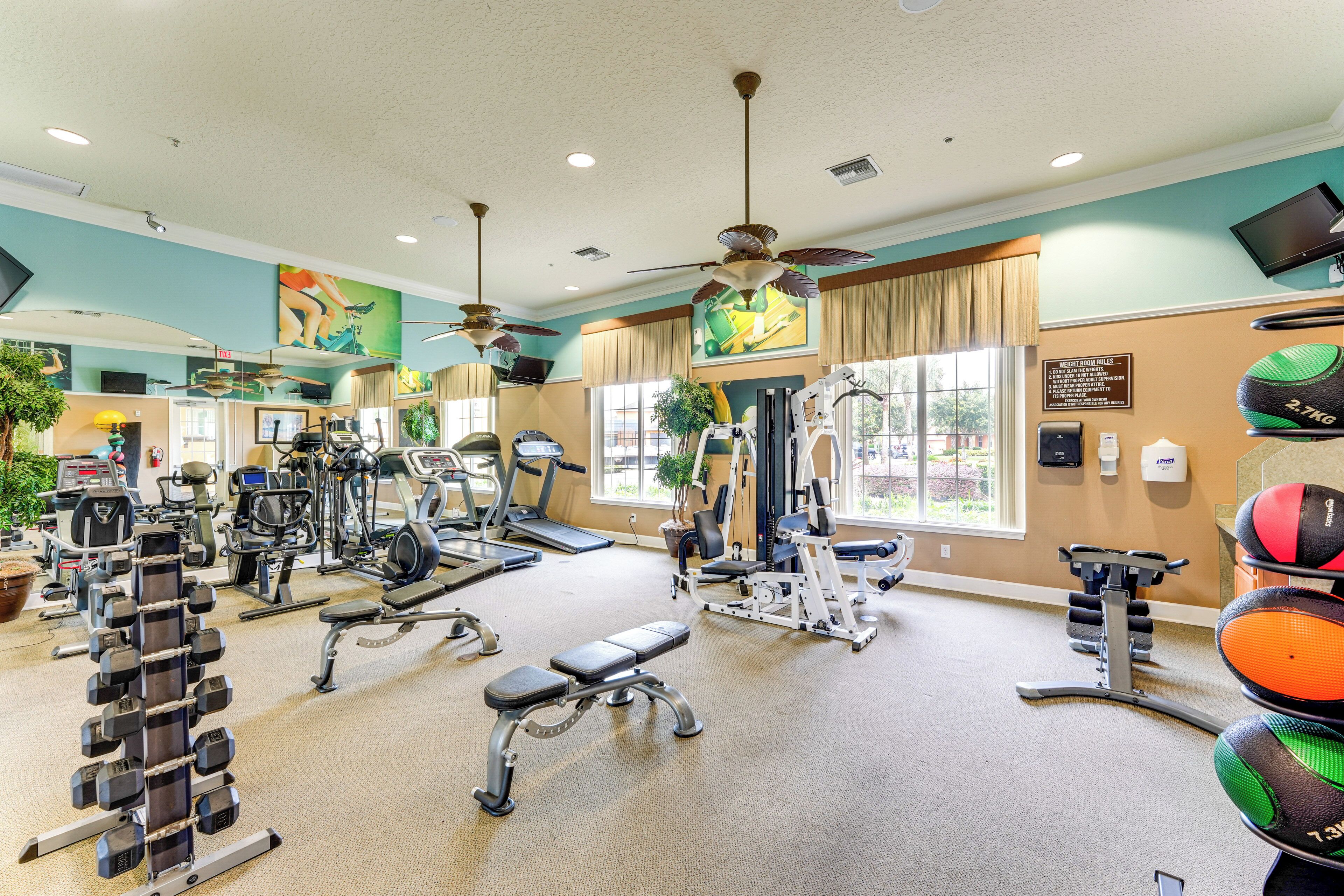 Une salle de sport équipée de divers appareils d’exercice, notamment des tapis de course, des haltères et des appareils de musculation.