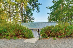 A house with a metal roof, surrounded by dense greenery and trees. - Hood Canal Views: Remote Cabin in Quilcene! (Quilcene)