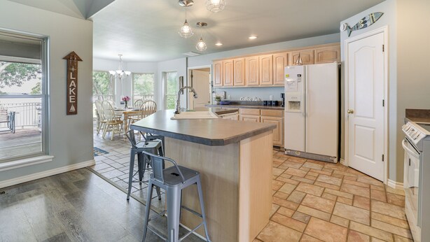 A modern kitchen with a central island, wooden cabinets, and a large window overlooking a deck. - Bring Your Boat! Lakefront Home w/ Dock in Grove (Grove)