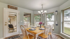 A dining area with a wooden table, white chairs, and a chandelier. - Bring Your Boat! Lakefront Home w/ Dock in Grove (Grove)