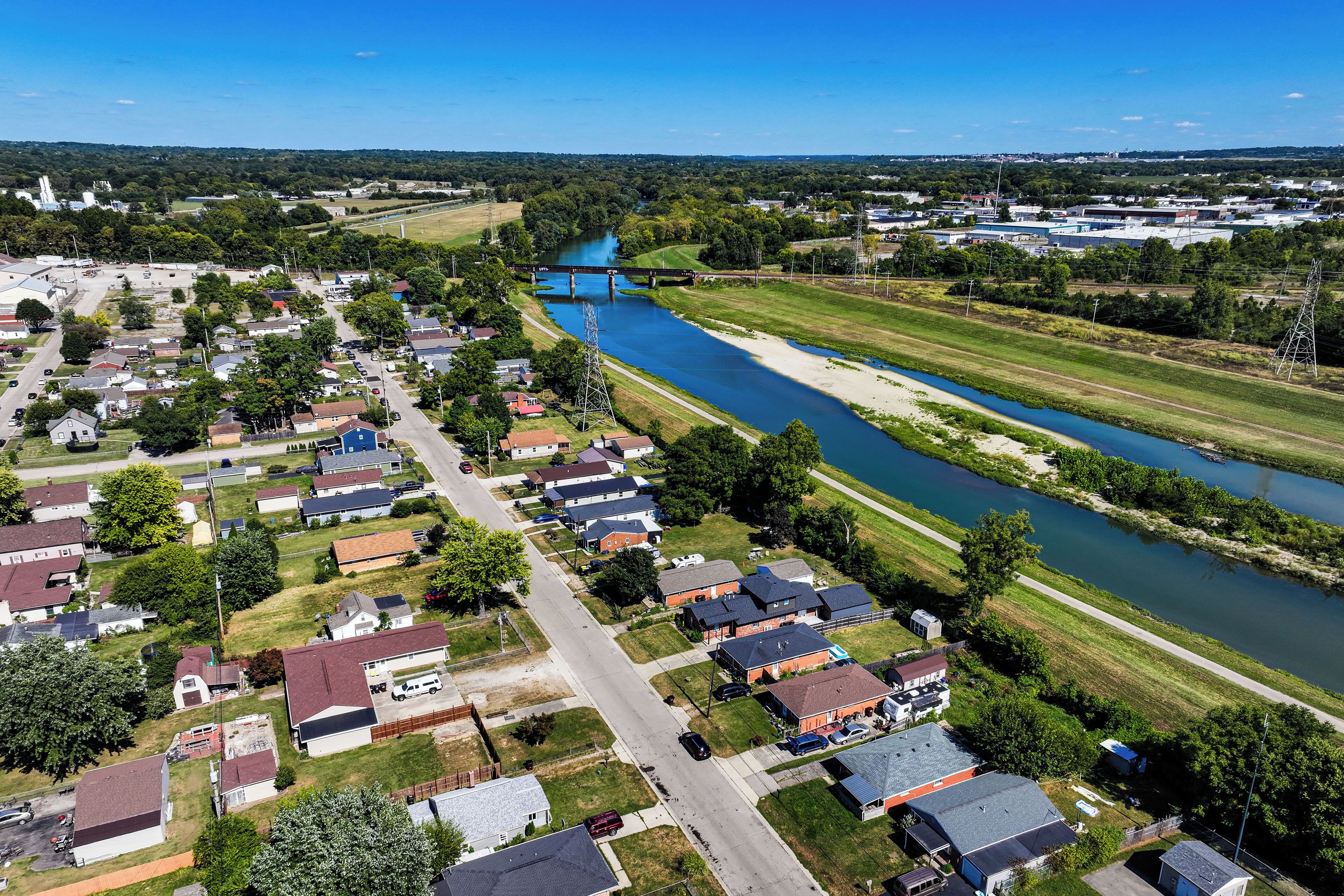 An aerial view of a residential area with houses, a river, and a bridge.