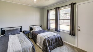 A bedroom with two beds, a ceiling fan, a window with curtains, and a door. - 2 Mi to Phillips 66 Refinery: Home w/ Yard (Borger)