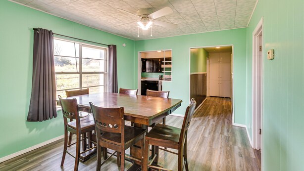 A dining area with a wooden table and chairs, a ceiling fan, and a view through a window. - 2 Mi to Phillips 66 Refinery: Home w/ Yard (Borger)