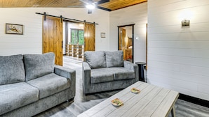 Uma sala de estar moderna com dois sofás cinzas, teto de madeira e uma porta de celeiro deslizante.