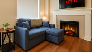 A modern living room with a sectional sofa, a fireplace, and a mounted TV displaying 'NETFLIX'.