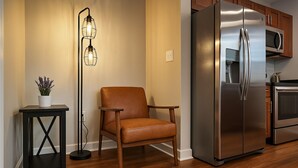 A modern kitchen with a stainless steel refrigerator, wooden cabinets, and a floor lamp.