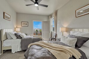 Ein Schlafzimmer mit zwei Betten, einem Deckenventilator und Blick nach draußen.