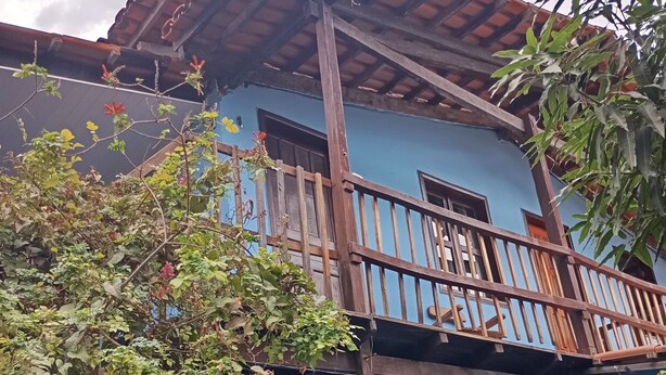 A blue building with a wooden balcony and a tiled roof. - New Dawn. (Alto Paraíso de Goiás)