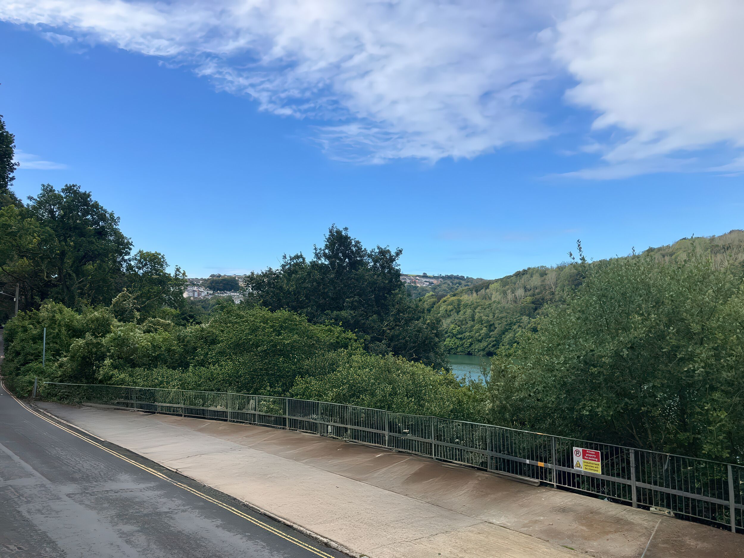 A bridge with a metal railing, a clear sky, and a river in the background.