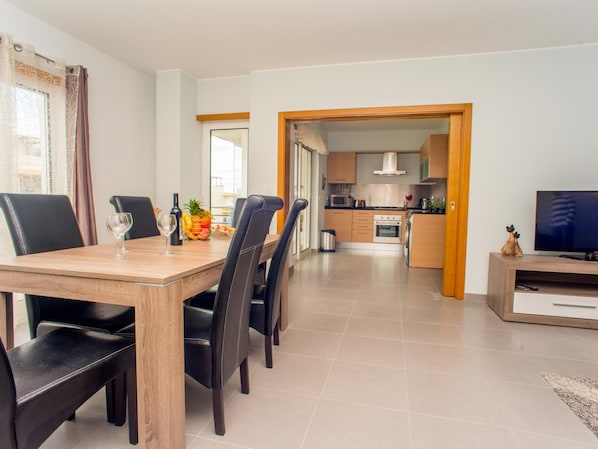 A modern apartment with a dining area, kitchen, and living space.