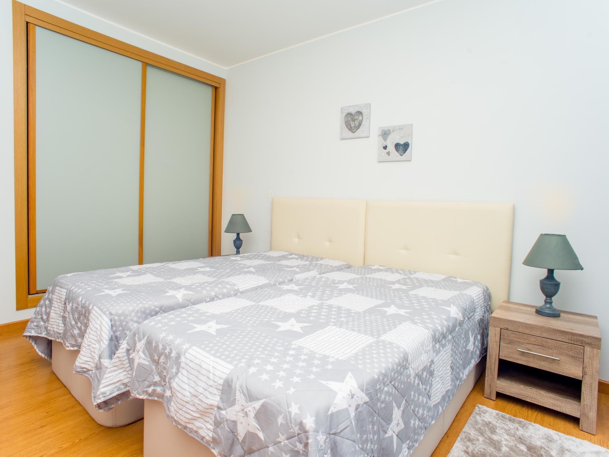 Una camera da letto con un letto, comodini, un tavolino da notte e una grande finestra.