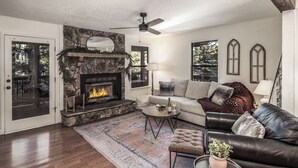Una sala de estar acogedora con chimenea de piedra, sofá de cuero y un ventanal grande.