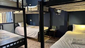 A bunk bed room with a window, a small table with bottles, and a wall-mounted shelf.