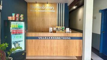A reception desk with a sign reading 'Villa Lakhang Thong' and a beverage dispenser to the left.