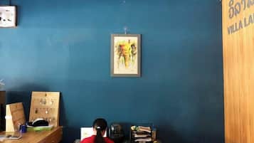 A room with a blue wall, a wooden cabinet, a desk with a computer, and a framed picture on the wall.