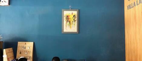 Una habitación con una pared azul, un armario de madera, un escritorio con una computadora y un cuadro enmarcado en la pared.