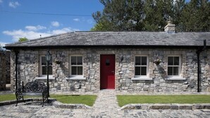 Un edificio de piedra con una puerta roja, escalones de piedra y un banco al frente.