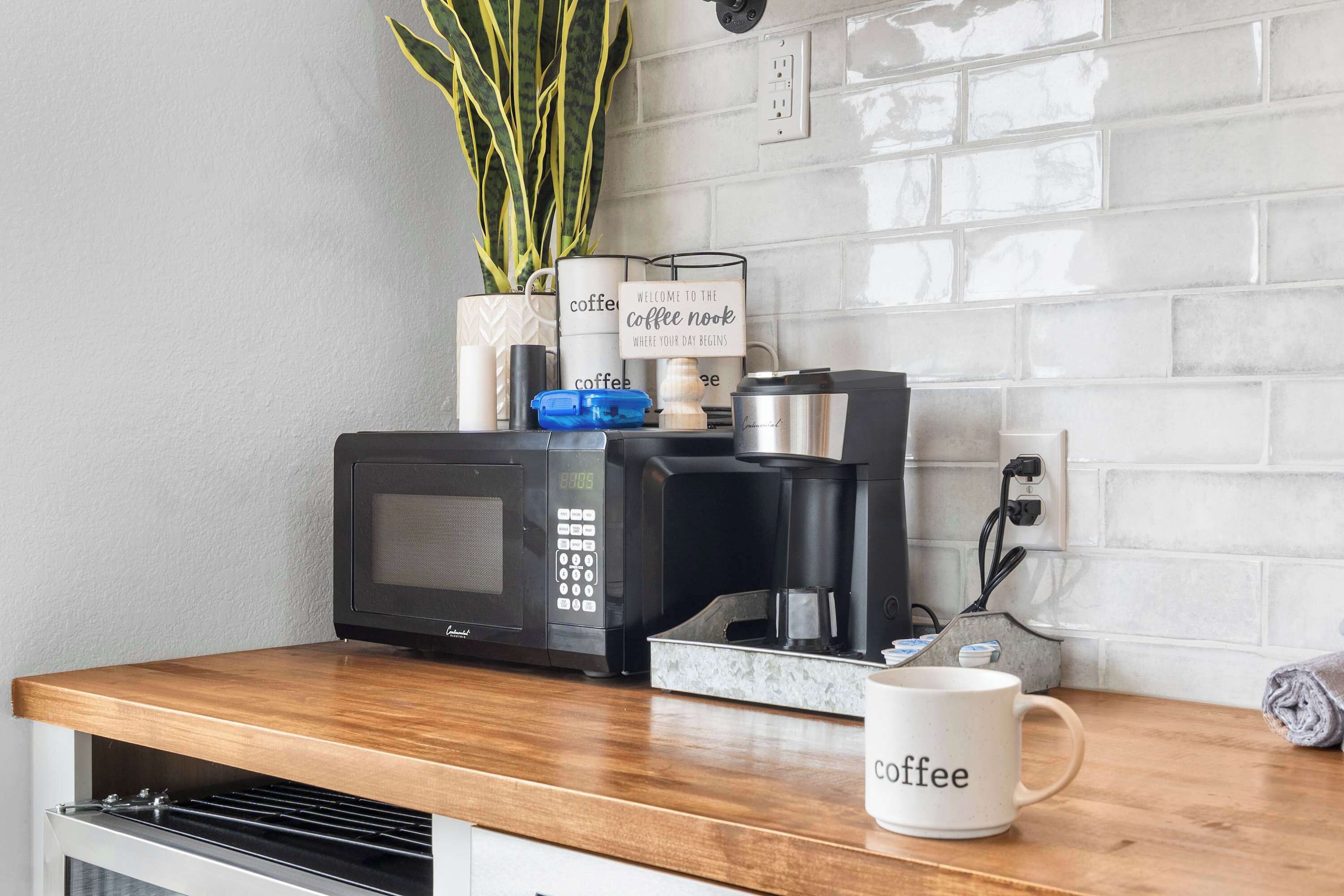 A kitchen counter with a coffee maker, a microwave, and a coffee mug.