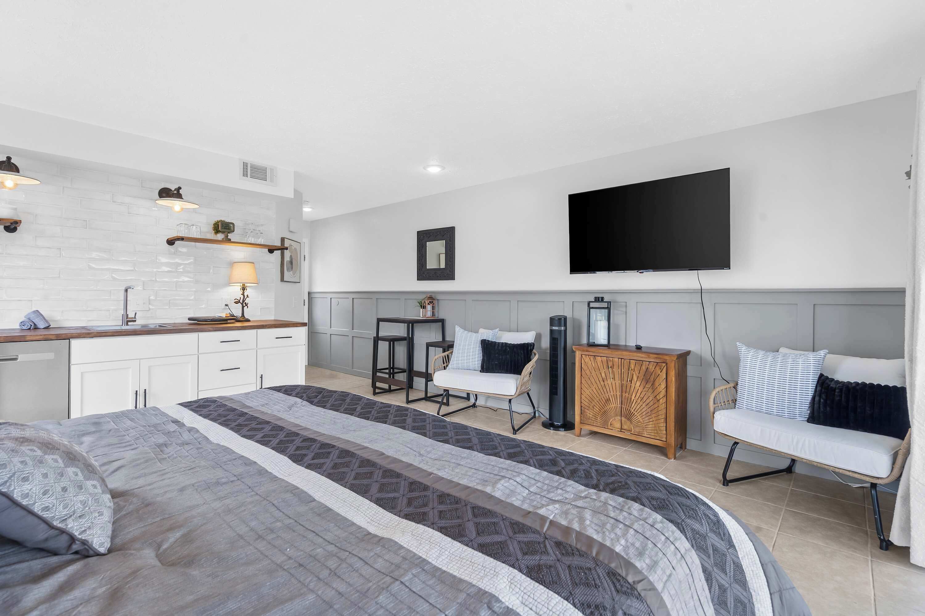 Une chambre à coucher moderne, dotée d’un grand lit, d’un bureau, d’une chaise, d’un téléviseur et d’une armoire.
