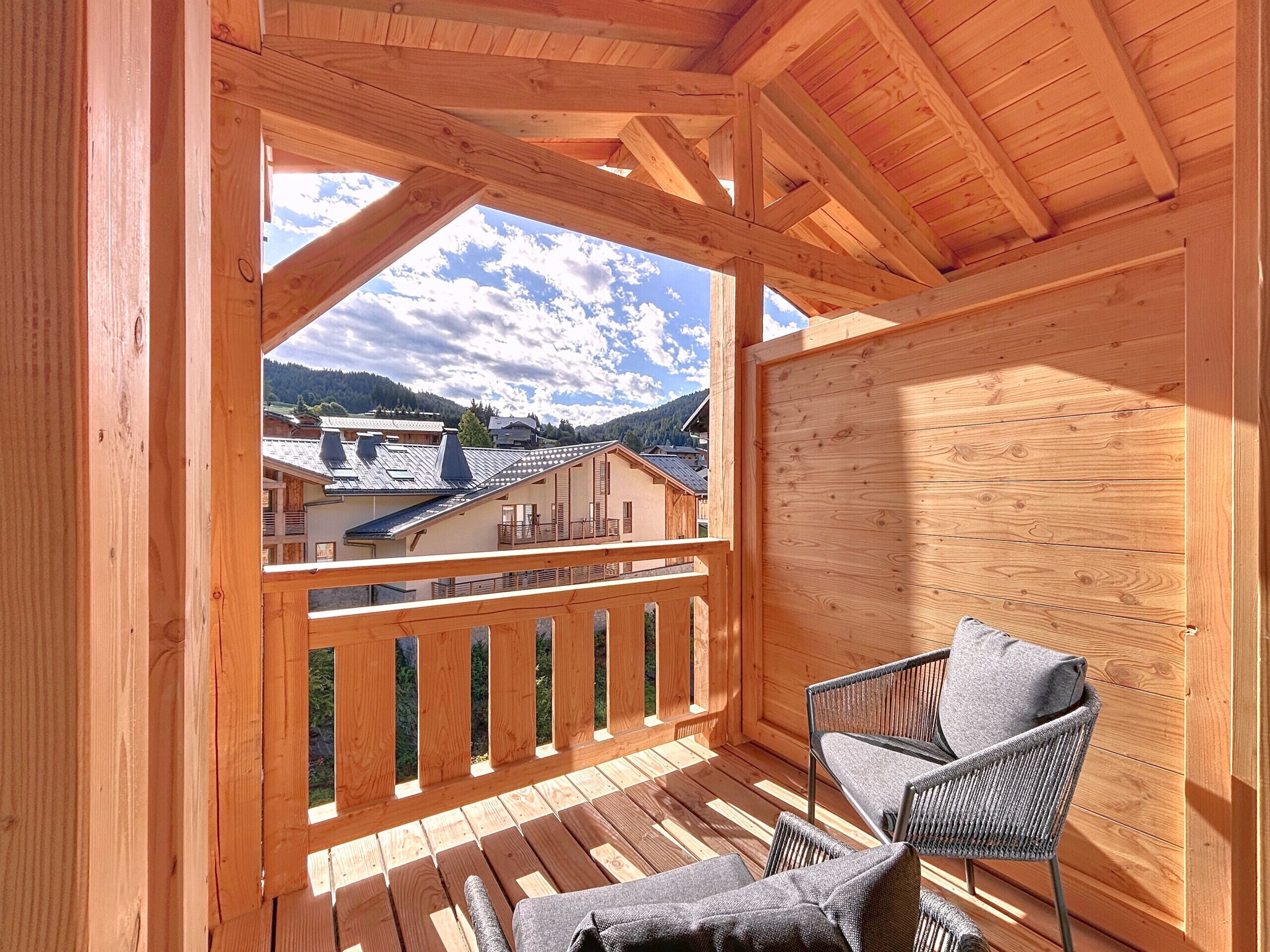 En träbalkong med utsikt över hus och berg.