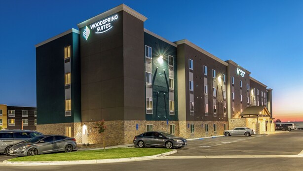 Un hôtel au design moderne, avec une enseigne bien visible indiquant « Woodspring Suites ».