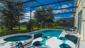 Ein überdachter Außenbereich mit Pool, Sitzgelegenheiten und einem Tisch mit blauem Geschirr.